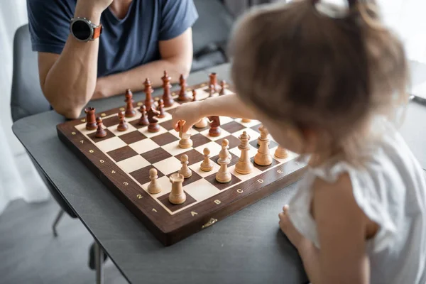 stock image Little girl playing chess with her father at the table in home kitchen. The concept early childhood development and education. Family leisure, communication and recreation. High quality photo
