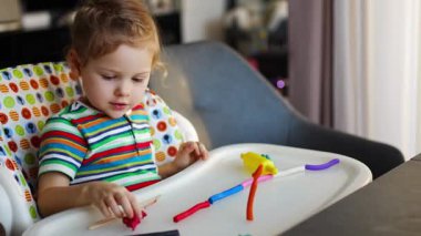 Little girl plays with multi-colored plasticine, creates different shapes. High quality 4k footage