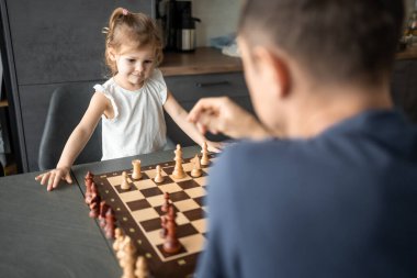 Baba küçük kızına evde mutfakta satranç oynamayı öğretiyor. Erken çocukluk gelişimi ve eğitim kavramı. Aile eğlencesi, iletişim ve eğlence. Yüksek kalite fotoğraf