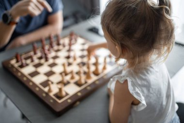 Baba küçük kızına evde mutfakta satranç oynamayı öğretiyor. Erken çocukluk gelişimi ve eğitim kavramı. Aile eğlencesi, iletişim ve eğlence. Yüksek kalite fotoğraf