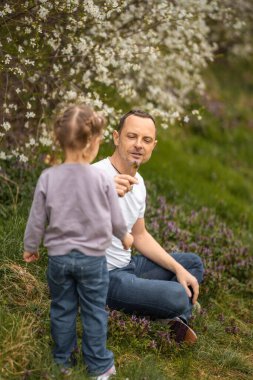 Baba ve kızı Prag, Avrupa 'daki Petrin Parkı' nda çiçek açan bir ağacın altında birlikte eğleniyorlar. Yüksek kalite fotoğraf