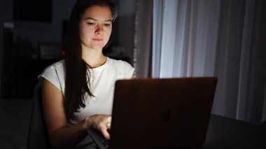 Casual beautiful woman working on a laptop at the night at home. High quality FullHD footage