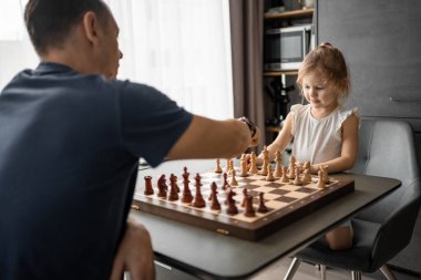 Baba küçük kızına evde mutfakta satranç oynamayı öğretiyor. Erken çocukluk gelişimi ve eğitim kavramı. Aile eğlencesi, iletişim ve eğlence. Yüksek kalite fotoğraf