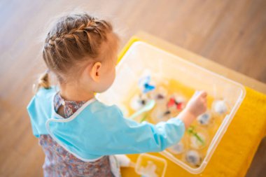 Küçük kız tuz ve suyla buzu eritiyor. Duyusal gelişim ve deneyimler, çocuklarla ilgili temalı aktiviteler, iyi motor beceriler geliştirme. Yüksek kalite fotoğraf