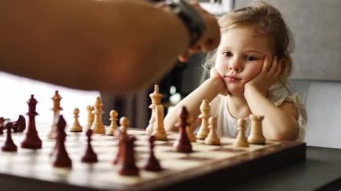 Baba küçük kızına evde mutfakta satranç oynamayı öğretiyor. Erken çocukluk gelişimini ve eğitimini hesaba katın. Aile eğlencesi, iletişim ve eğlence. Yüksek kalite 4k görüntü