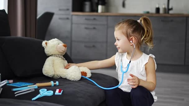 Mała Dziewczynka Bawiąca Się Doktora Zabawkami Misiaczkiem Kanapie Salonie Domu — Wideo stockowe
