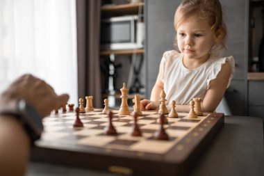 Baba küçük kızına evde mutfakta satranç oynamayı öğretiyor. Erken çocukluk gelişimi ve eğitim kavramı. Aile eğlencesi, iletişim ve eğlence. Yüksek kalite fotoğraf