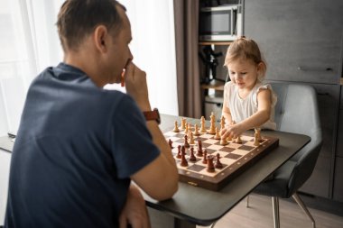 Baba küçük kızına evde mutfakta satranç oynamayı öğretiyor. Erken çocukluk gelişimi ve eğitim kavramı. Aile eğlencesi, iletişim ve eğlence. Yüksek kalite fotoğraf