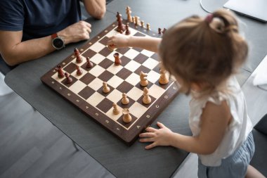 Baba küçük kızına evde mutfakta satranç oynamayı öğretiyor. Erken çocukluk gelişimi ve eğitim kavramı. Aile eğlencesi, iletişim ve eğlence. Yüksek kalite fotoğraf