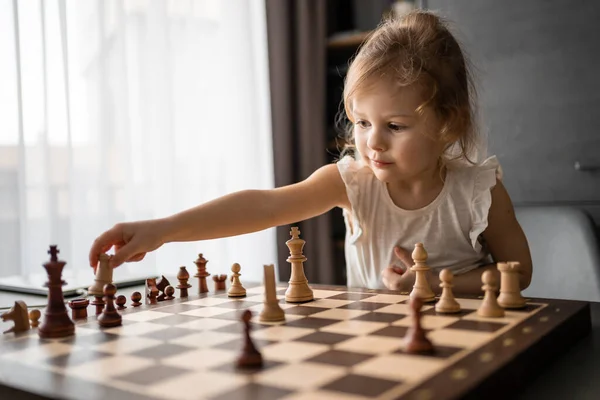 stock image Little girl playing chess at the table in home kitchen. The concept early childhood development and education. Family leisure, communication and recreation. High quality photo