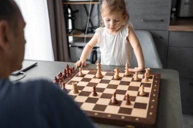 Baba küçük kızına evde mutfakta satranç oynamayı öğretiyor. Erken çocukluk gelişimi ve eğitim kavramı. Aile eğlencesi, iletişim ve eğlence. Yüksek kalite fotoğraf