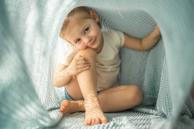 Küçük kız güneşli bir sabah mavi örgü ekose altında eğleniyor. Yüksek kalite fotoğraf