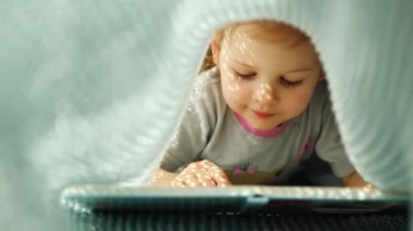 Küçük kız, güneşli bir sabahta mavi örülmüş ekose bir kitabın altında eleştiri yapmaktan zevk alıyor. Yüksek kalite 4k görüntü