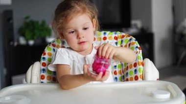 Küçük kız ev yapımı pembe bir balçıkla oynuyor. Evde sümüklü oyuncak oynayan çocuk elleri. Yüksek kalite 4k görüntü