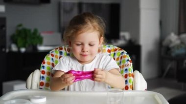 Küçük kız ev yapımı pembe bir balçıkla oynuyor. Evde sümüklü oyuncak oynayan çocuk elleri. Yüksek kalite 4k görüntü