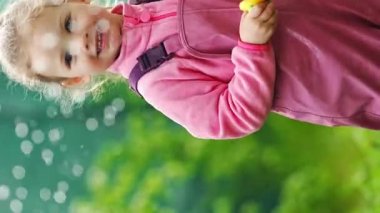 2-3 yaşlarında su geçirmez kıyafetler giyen mutlu bir çocuk arka bahçede su tabancasıyla eğleniyor. Yüksek kalite 4k görüntü