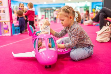 Prag, Çek Cumhuriyeti - 27 Nisan 2023: Çek Cumhuriyeti 'nin Prag kentindeki Letnany alışveriş merkezinde Barbie oyuncakları ve Hot Wheels ile çocuk oyun odasında oynayan küçük kız. Yüksek kalite fotoğraf
