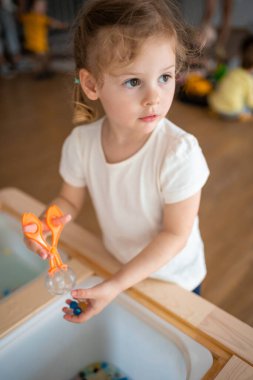 Duyusal su boncuklarıyla oynayan küçük bir kız, hidrojel topları. Duyusal gelişim ve deneyimler, çocuklarla ilgili temalı aktiviteler, iyi motor beceriler geliştirme. Yüksek kalite fotoğraf