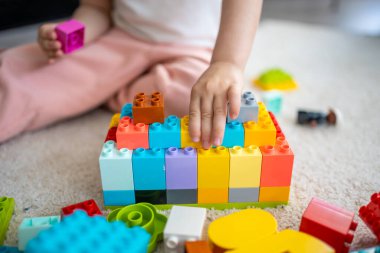 Küçük kız evde inşaatçı oyuncağıyla oynuyor, eğitici bir oyun oynuyor, boş zamanlarını boş zamanlarında geçiriyor. Yüksek kalite fotoğraf