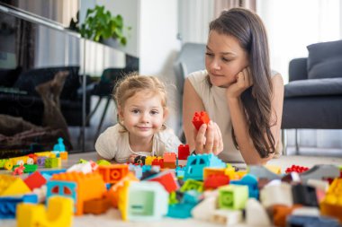Küçük kız evde anne ya da kadın bebek bakıcısıyla evde inşaat oyuncağıyla oynuyor, eğitim oyunu oynuyor, aile evde boş zamanlarını birlikte geçiriyor. Yüksek kalite fotoğraf