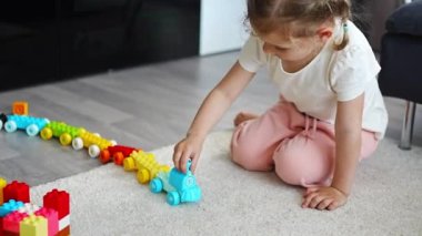 Küçük kız evde inşaatçı oyuncağıyla oynuyor, eğitici bir oyun oynuyor, boş zamanlarını boş zamanlarında geçiriyor. Yüksek kalite 4k görüntü