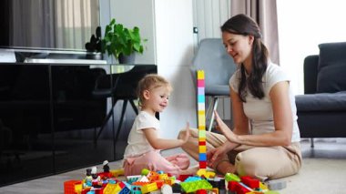 Küçük kız evde anne ya da kadın bebek bakıcısıyla evde inşaat oyuncağıyla oynuyor, eğitim oyunu oynuyor, aile evde boş zamanlarını birlikte geçiriyor. Yüksek kalite 4k görüntü