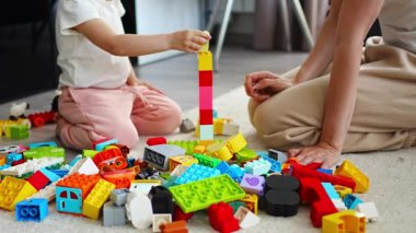 Küçük kız evde anne ya da kadın bebek bakıcısıyla evde inşaat oyuncağıyla oynuyor, eğitim oyunu oynuyor, aile evde boş zamanlarını birlikte geçiriyor. Yüksek kalite 4k görüntü