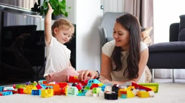 Küçük kız evde anne ya da kadın bebek bakıcısıyla evde inşaat oyuncağıyla oynuyor, eğitim oyunu oynuyor, aile evde boş zamanlarını birlikte geçiriyor. Yüksek kalite 4k görüntü