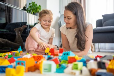 Küçük kız evde anne ya da kadın bebek bakıcısıyla evde inşaat oyuncağıyla oynuyor, eğitim oyunu oynuyor, aile evde boş zamanlarını birlikte geçiriyor. Yüksek kalite fotoğraf