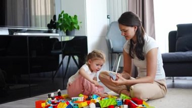 Küçük kız evde anne ya da kadın bebek bakıcısıyla evde inşaat oyuncağıyla oynuyor, eğitim oyunu oynuyor, aile evde boş zamanlarını birlikte geçiriyor. Yüksek kalite 4k görüntü