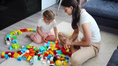 Küçük kız evde anne ya da kadın bebek bakıcısıyla evde inşaat oyuncağıyla oynuyor, eğitim oyunu oynuyor, aile evde boş zamanlarını birlikte geçiriyor. Yüksek kalite 4k görüntü