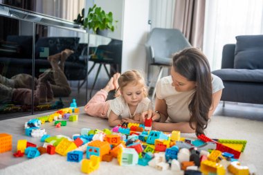 Küçük kız evde anne ya da kadın bebek bakıcısıyla evde inşaat oyuncağıyla oynuyor, eğitim oyunu oynuyor, aile evde boş zamanlarını birlikte geçiriyor. Yüksek kalite fotoğraf