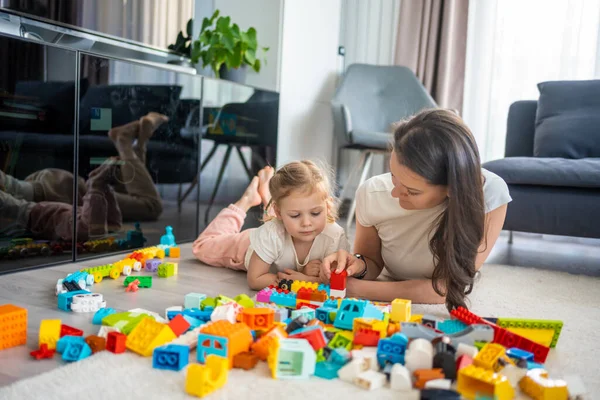 stock image Little girl play with constructor toy on floor in home with mom or woman babysitter, educational game, family at home spend leisure activities time together concept. High quality photo