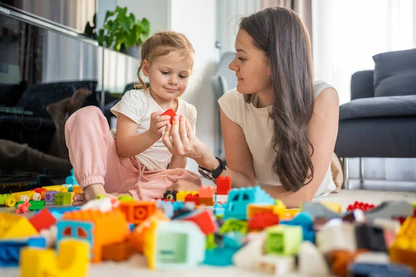 Küçük kız evde anne ya da kadın bebek bakıcısıyla evde inşaat oyuncağıyla oynuyor, eğitim oyunu oynuyor, aile evde boş zamanlarını birlikte geçiriyor. Yüksek kalite fotoğraf