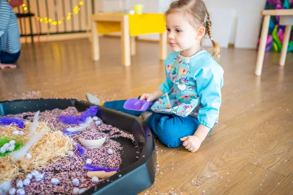 stock image Little girl playing with sensory colorful rice. Sensory development and experiences, themed activities with children, fine motor skills development. High quality photo