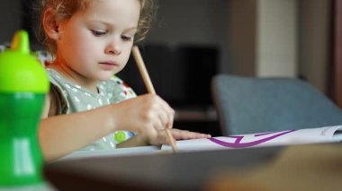 Küçük kız boya işlemini seviyor, boya fırçasını suluboya olarak kullanıyor, çocuk odaklı işlem. Yüksek kalite 4k görüntü
