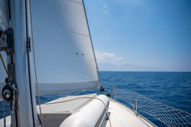Açık denizde yat gezintisi. Güvertenin yakın görüntüsü, direk ve yelkenler. Temiz gökyüzü, dalgalar ve su sıçramaları. Yüksek kalite fotoğraf