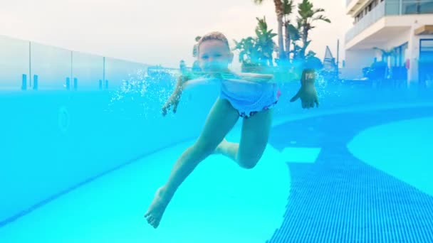소녀는 굽이치는 반지를 여름에 수영장에서 수영한다 아이들은 럭셔리 리조트 수영장에서 — 비디오