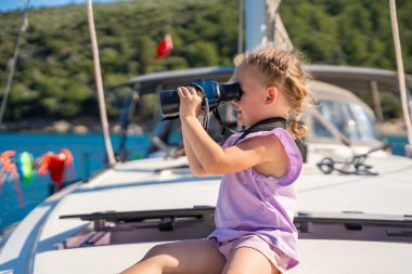 Yatta dürbünle denize bakan küçük bir kız. Yüksek kalite fotoğraf