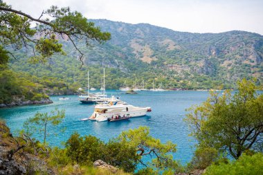 Fethie, Türkiye - 4 Haziran 2023: Fethie, Türkiye yakınlarındaki güzel deniz kıyısı Kleopatra Hamamı. Bozkır yatları, berrak mavi sular ve çam ağaçları olan yaz manzarası. Yüksek kalite fotoğraf