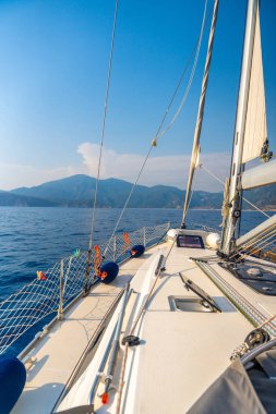 Açık denizde yat gezintisi. Güvertenin yakın görüntüsü, direk ve yelkenler. Temiz gökyüzü, dalgalar ve su sıçramaları. Yüksek kalite fotoğraf
