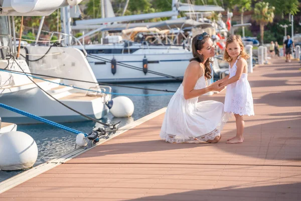Mutlu anne-kız çocuğu marinada lüks yatlarda eğleniyor. Aile seyahati, yaşam tarzı, tatil konsepti. Yüksek kalite fotoğraf