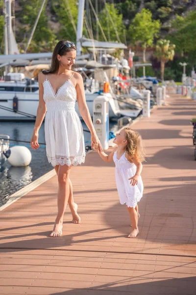 Mutlu anne-kız çocuğu marinada lüks yatlarda eğleniyor. Aile seyahati, yaşam tarzı, tatil konsepti. Yüksek kalite fotoğraf