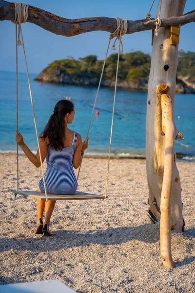 stock image Young woman on wooden swing on Oludeniz beach. Summer holiday in Oludeniz, Turkey. Girl ride on a swing on sea coast, clear water. Travel concept. High quality photo