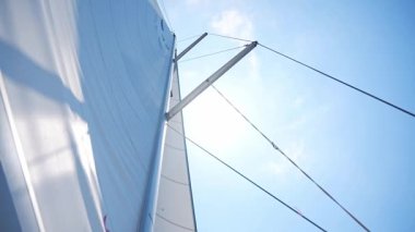 Açık denizde yat gezintisi. Rüzgarda yelkenli bir yatın ve güneşli berrak gökyüzünün yakın görüntüsü. Yüksek kalite 4k görüntü