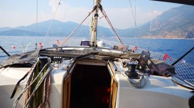 Açık denizde yat gezintisi. Güvertenin yakın görüntüsü, direk ve yelkenler. Temiz gökyüzü, dalgalar ve su sıçramaları. Yüksek kalite 4k görüntü
