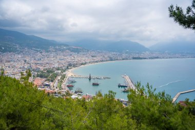Bulutlu bir günde Türkiye 'nin güney kıyısında limanı ve plajı olan havacılık manzaralı tatil beldesi Alanya. Yüksek kalite fotoğraf