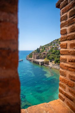 Türkiye 'nin Alanya kentindeki Kizil Kule kulesi yakınlarındaki antik tersane veya Tersane ve güzel plaj ve sakin turkuaz deniz yüzeyi. Yüksek kalite fotoğraf