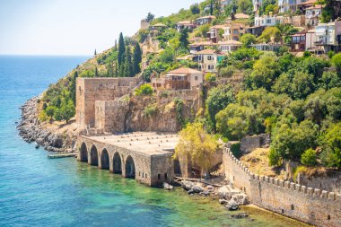Türkiye 'nin Alanya kentindeki Kizil Kule kulesi yakınlarındaki antik tersane veya Tersane ve güzel plaj ve sakin turkuaz deniz yüzeyi. Yüksek kalite fotoğraf