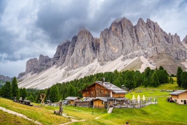 Puez Odle Doğa Parkı 'ndaki Dolomite manzarası. Alp yaylalarından ahşap evler ve yeşil çayırlar görünüyor. Yüksek kalite fotoğraf